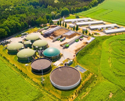 Aerial view over biogas plant and farm in green fields