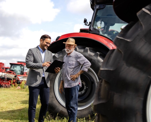 Two people discussing loans in front of tractors