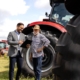 Two people discussing loans in front of tractors